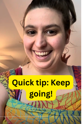 Mama & Roo's founder smiles in a screenshot of the latest Quick Tip video on how to be more comfortable while babywearing. She is wearing her baby on her back in a wrap strap meh dai, available at mama-roo.com. Text reads, "Quick tip: Keep going!"