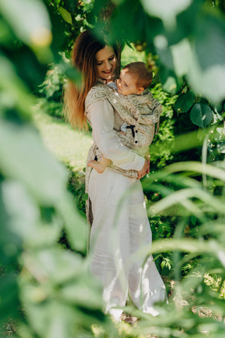 A mom carrying her baby in the LennyLamb Hybrid, Infinity - Golden Hour design. 