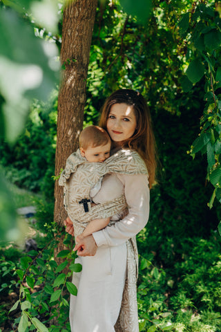 A mom carrying her baby in the LennyLamb Hybrid, Infinity - Golden Hour design. 