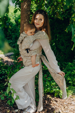 A mom carrying her baby in the LennyLamb Hybrid, Infinity - Golden Hour design. 