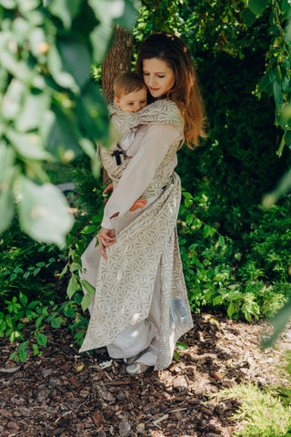 A mom carrying her baby in the LennyLamb Hybrid, Infinity - Golden Hour design. 