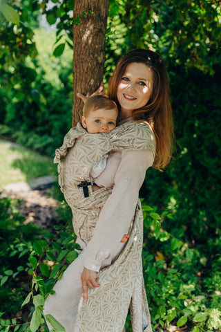 A mom carrying her baby in the LennyLamb Hybrid, Infinity - Golden Hour design. 