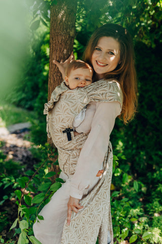 A mom carrying her baby in the LennyLamb Hybrid, Infinity - Golden Hour design. 