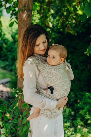 A mom carrying her baby in the LennyLamb Hybrid, Infinity - Golden Hour design. 