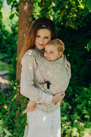 A mom carrying her baby in the LennyLamb Hybrid, Infinity - Golden Hour design. 