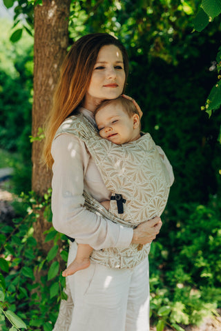 A mom carrying her baby in the LennyLamb Hybrid, Infinity - Golden Hour design. 