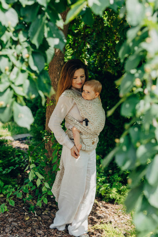 A mom carrying her baby in the LennyLamb Hybrid, Infinity - Golden Hour design. 
