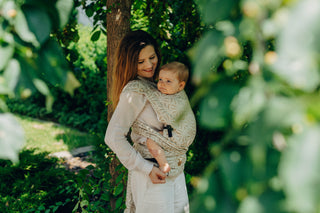 A mom carrying her baby in the LennyLamb Hybrid, Infinity - Golden Hour design. 