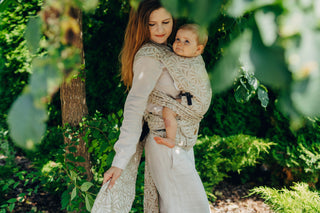 A mom carrying her baby in the LennyLamb Hybrid, Infinity - Golden Hour design. 