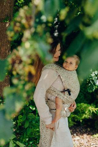 A mom carrying her baby in the LennyLamb Hybrid, Infinity - Golden Hour design. 