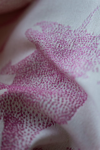Close-up of white fabric with pink dinosaurs - showing detail of weave and sparkle threads - Jurassic Park Princess REVERSE preorder woven wrap fabric, available for a limited time at Mama & Roo's