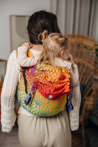 Preschool size wrap conversion waist-less onbuhimo baby backpack carrier for children from 3-7 years old in cotton woven design Rainbow Lotus, a jacquard weave with a bold rainbow gradient under an outlined repeating lotus flower pattern