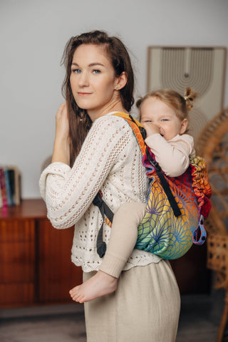 Preschool size wrap conversion waist-less onbuhimo baby backpack carrier for children from 3-7 years old in cotton woven design Rainbow Lotus, a jacquard weave with a bold rainbow gradient under an outlined repeating lotus flower pattern
