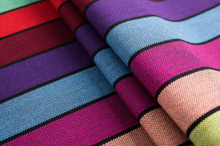 Lenny Lamb Long Woven Wrap - Carousel of Colors - Fabric close up. Wrap has horizontal stripes in rainbow colors with thin black stripes in-between the colors