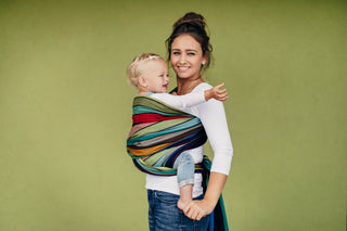 Lenny Lamb Long Woven Wrap - Carousel of Colors - toddler torso carry side view. Wrap has horizontal stripes in rainbow colors with thin black stripes in-between the colors