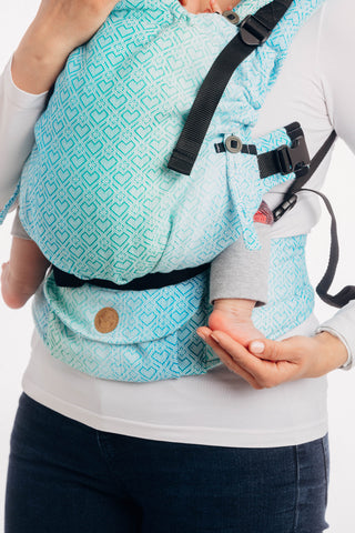 Older version for example only - SSC newborn adapter in position on a Lenny Upgrade carrier. You can see how the strap is used in place of the shoulder strap clip and wraps around baby's bottom, shortening the panel.